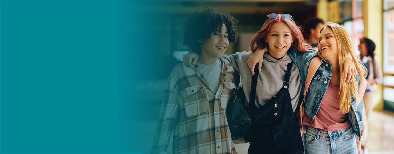 Happy teenage students walking together in a school hallway, smiling and enjoying each other's company.